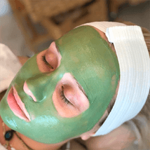 A woman with green facial mask on her face.